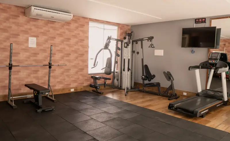 Academia da clínica com esteira, estação de musculação e piso emborrachado