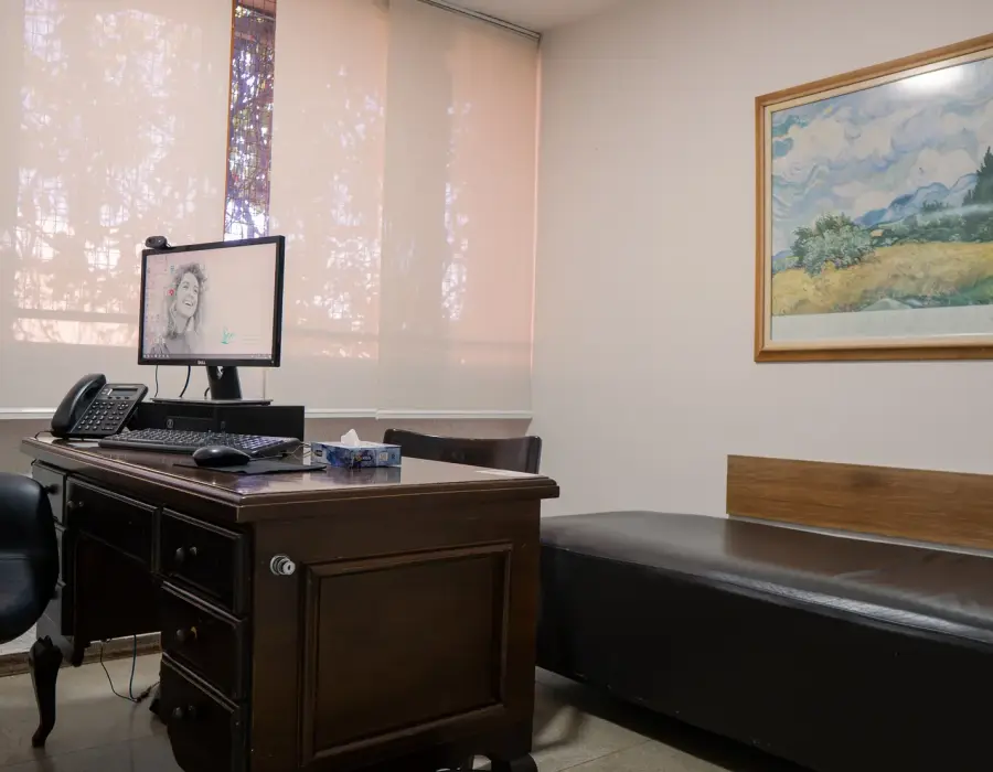Consultório de psicoterapia com divã, mesa de atendimento e janela ampla