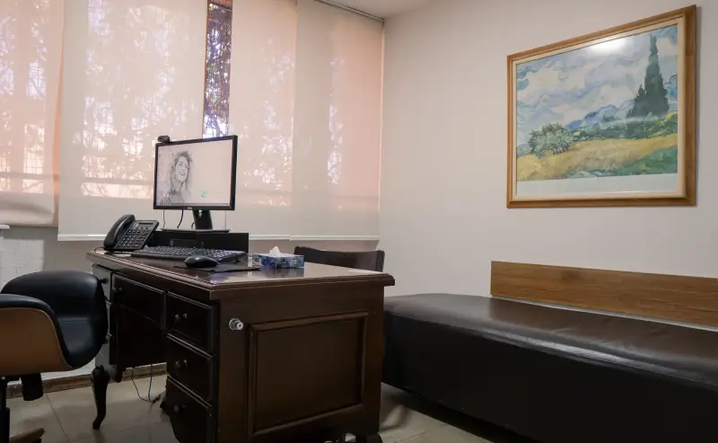 Consultório de psicoterapia com divã, mesa de atendimento e janela ampla