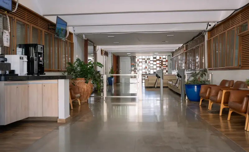 Corredor de acesso da clínica com poltronas de espera, plantas e luz natural