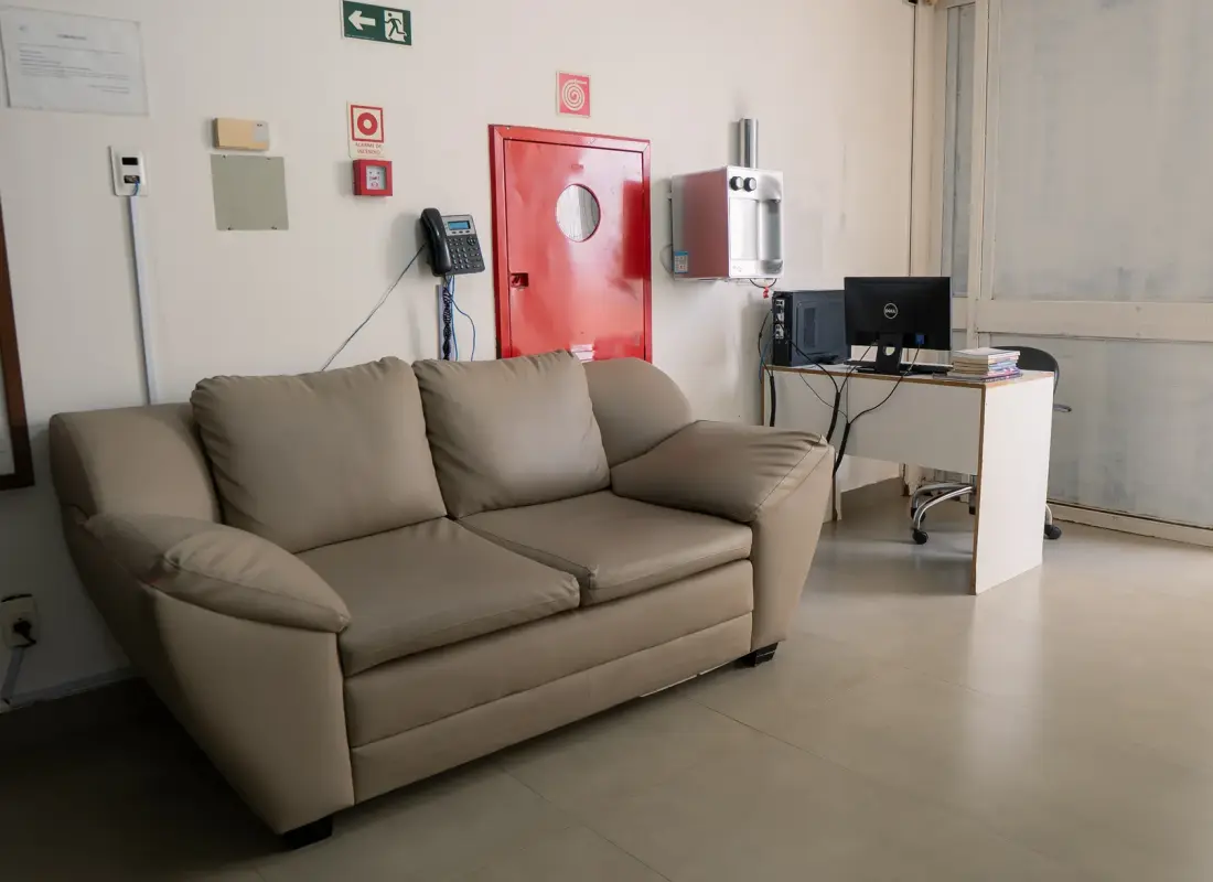 Sala de espera interna com sofá e posto de atendimento