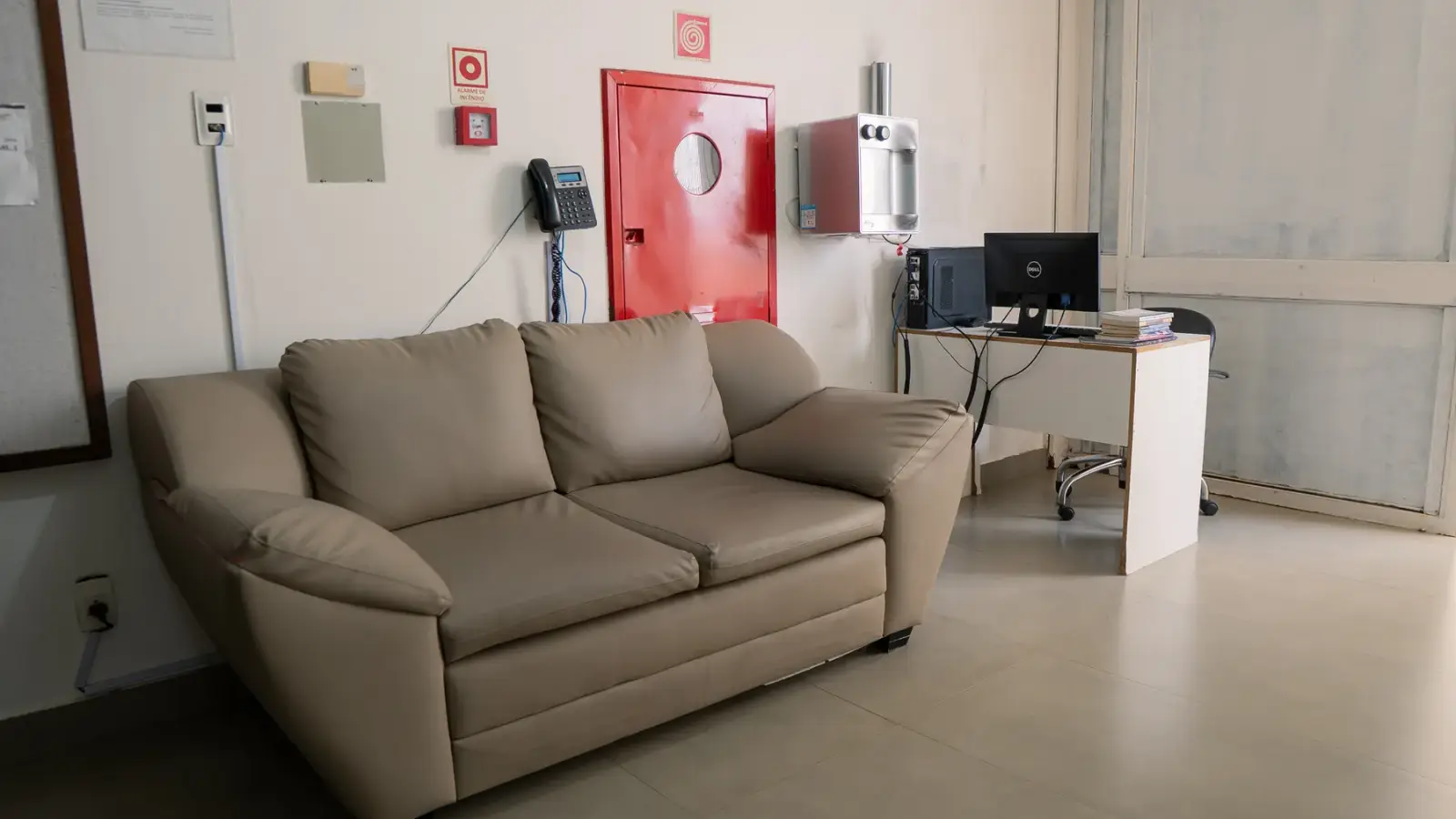 Sala de espera interna com sofá e posto de atendimento
