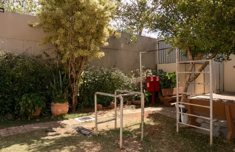 Área verde com barras de alongamento e canteiro florido