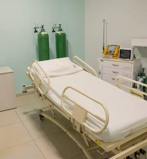 Leito de urgência com cama hospitalar, monitor multiparâmetro e cilindros de oxigênio