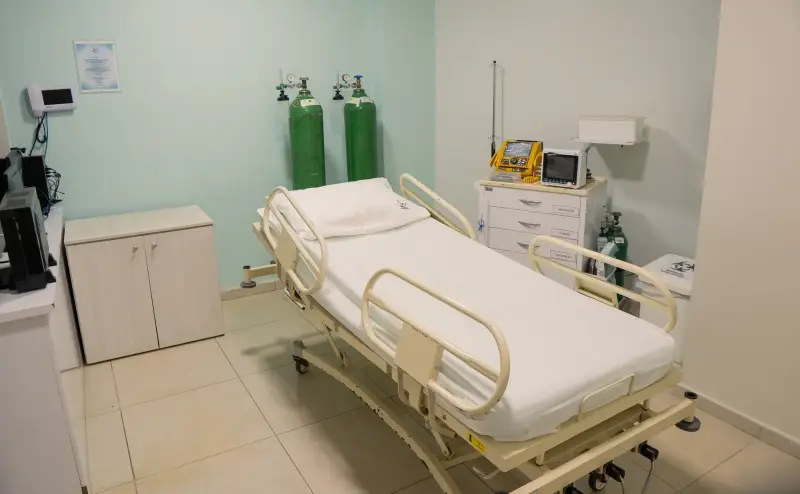Leito de urgência com cama hospitalar, monitor multiparâmetro e cilindros de oxigênio