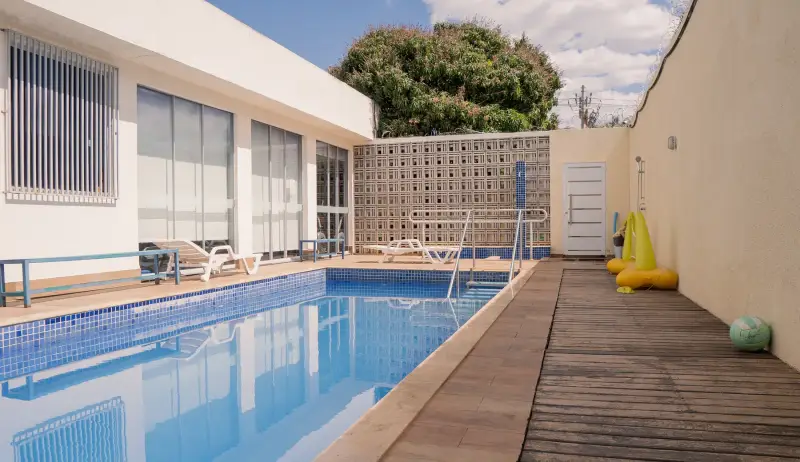 Piscina da área externa com deck de madeira e espreguiçadeiras