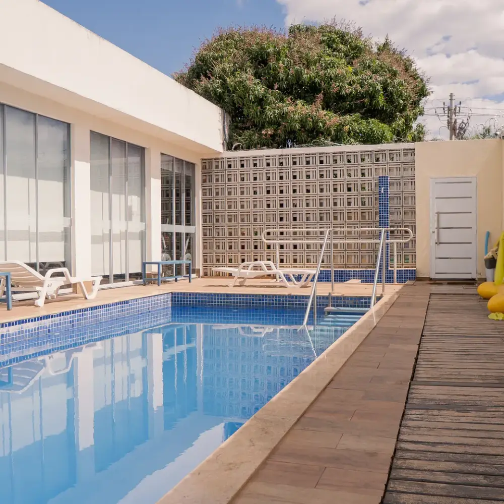 Piscina da área externa com deck de madeira e espreguiçadeiras