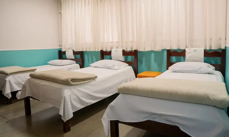 Quarto de internação com camas individuais, cortinas e enxoval branco