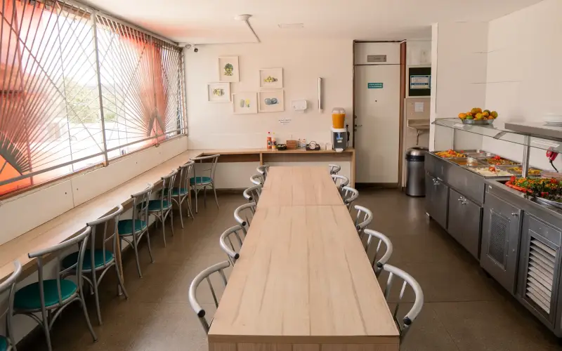 Refeitório com mesa comunitária e balcão térmico de refeições