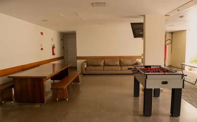 Área de jogos coberta com mesa de pebolim, bancos e sofá