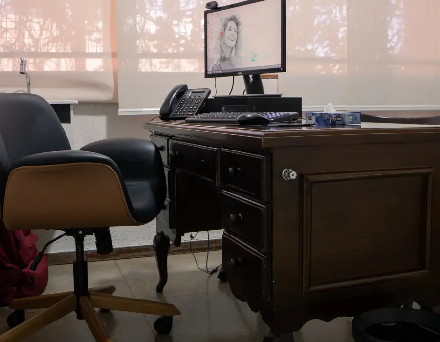 Consultório equipado para teleconsulta, com monitor e telefone sobre a mesa